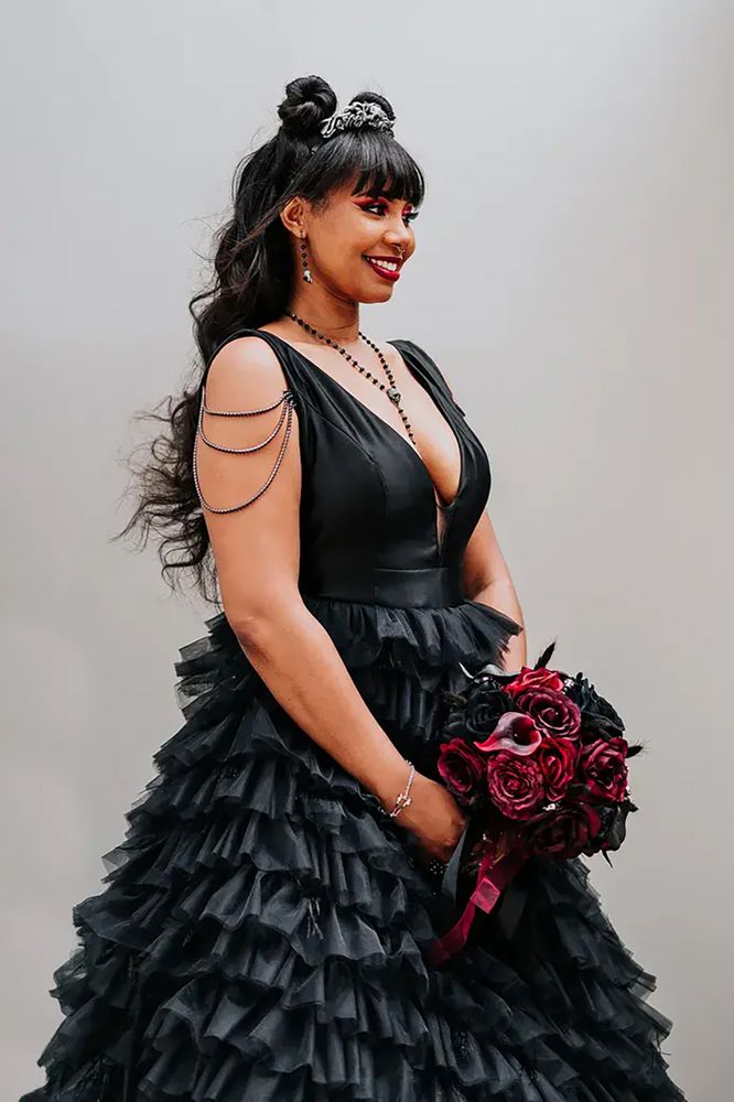 Bride wears black wedding dress with low front and ruffled full skirt with a gothic feel