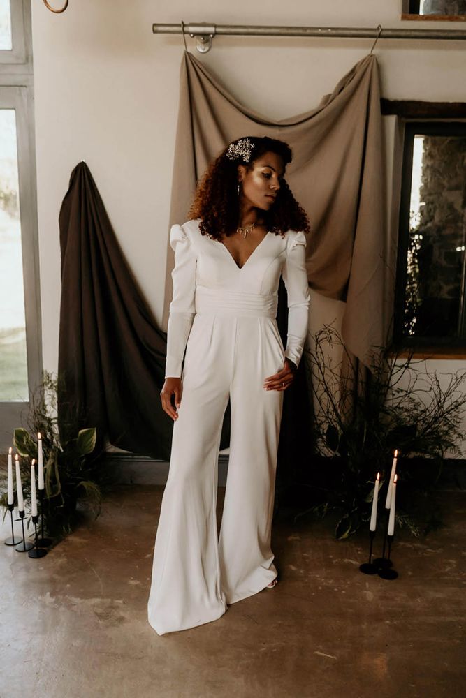 Bride wears double breasted white suit complete with wide leg trousers and neutral heels 