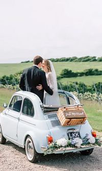 Bride and groom standing inside a vintage baby blue wedding car decorated with flowers and a 'Just Married' sign - Wedding Transport