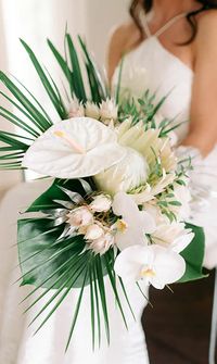 Bride holding a tropical-style simple wedding bouquet with white orchids - Florists