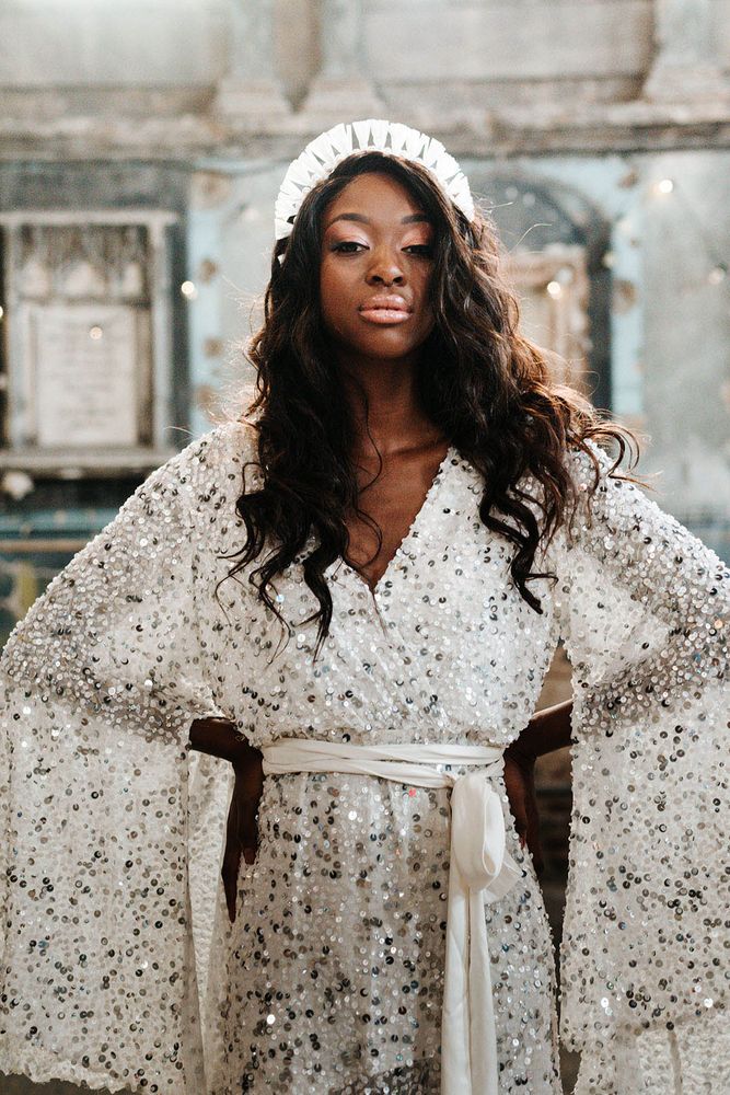 Bride wears sequin wedding dress complete with batwing sleeves and wrap around waist with white tie