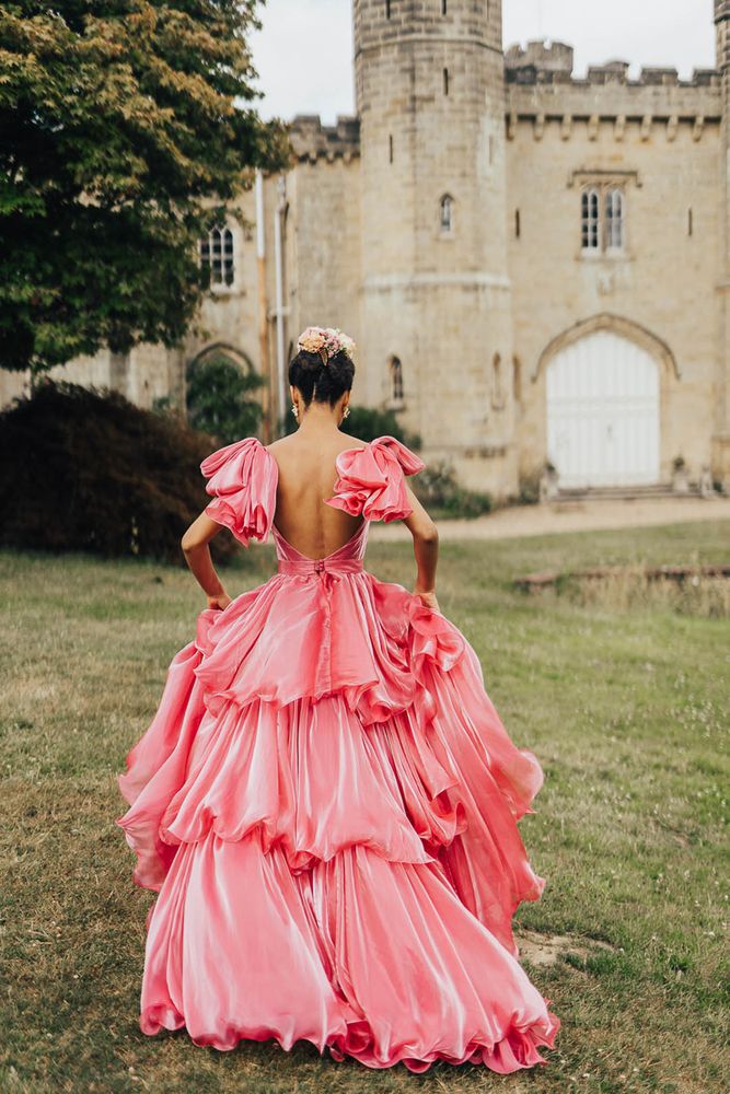 Bride wears shimmering pink Emma Beaumont wedding dress with ruffled styling and bow sleeves