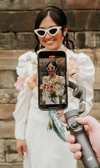 A content creator films a stylish bride in sunglasses using a phone on a gimbal - Wedding Content Creators