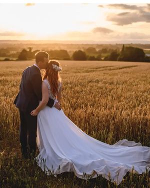Dewsall Court sustainable wedding venue, couple embracing in a field on their wedding day