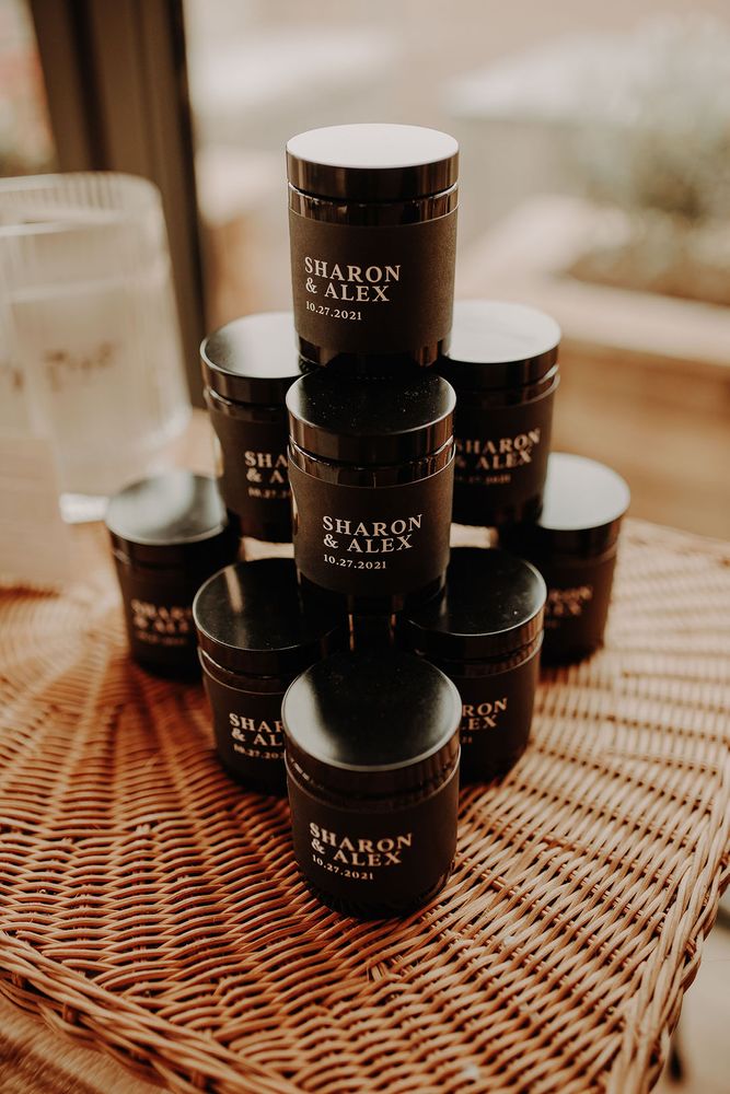 Stack of sleek black glass candles with personalised label for wedding favours 