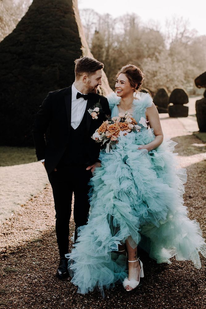 Bride wears princess styled ruffled light blue wedding dress with white heeled shoes 