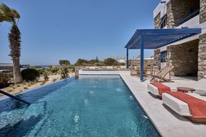 Private pool suite at Mykonos Theoxenia Hotel featuring terrace with loungers, pergola-covered dining area, and Mykonos windmill views