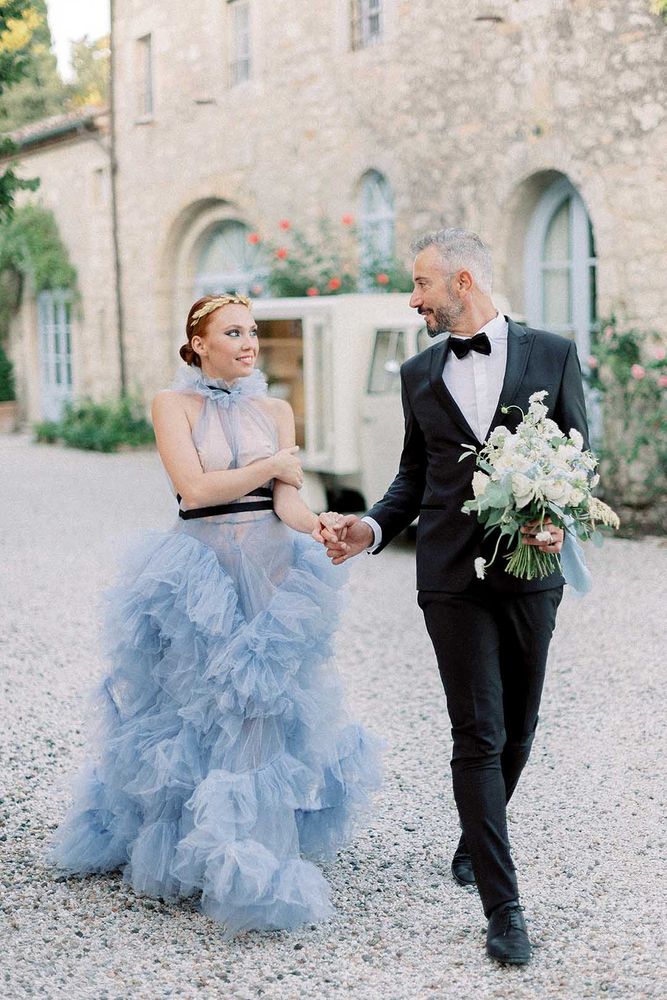 Bride wears full ruffled skirt pale blue wedding dress at destination wedding with groom in a tuxedo