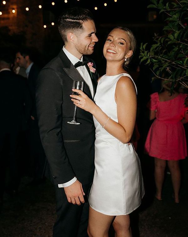 Bride in short wedding reception dress for the city wedding with the groom in a black tux