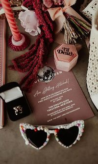 Flat lay of wedding accessories including sunglasses, candles, and invitation cards - Wedding Decor, Hire & Styling