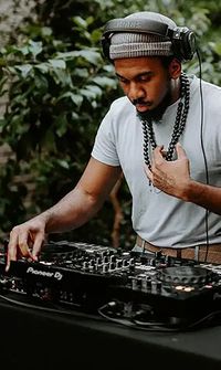 Wedding DJ wearing headphones mixes music on a professional DJ deck outdoors - Wedding Entertainment