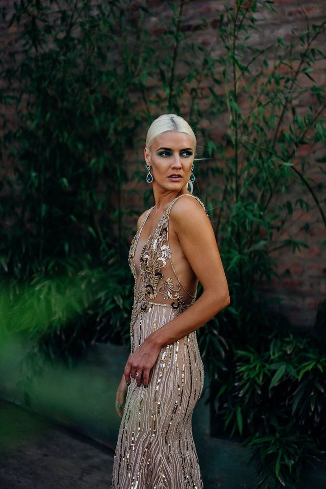 Bride wears fitted embellished white and gold wedding dress with sequins and bold green eyeshadow makeup